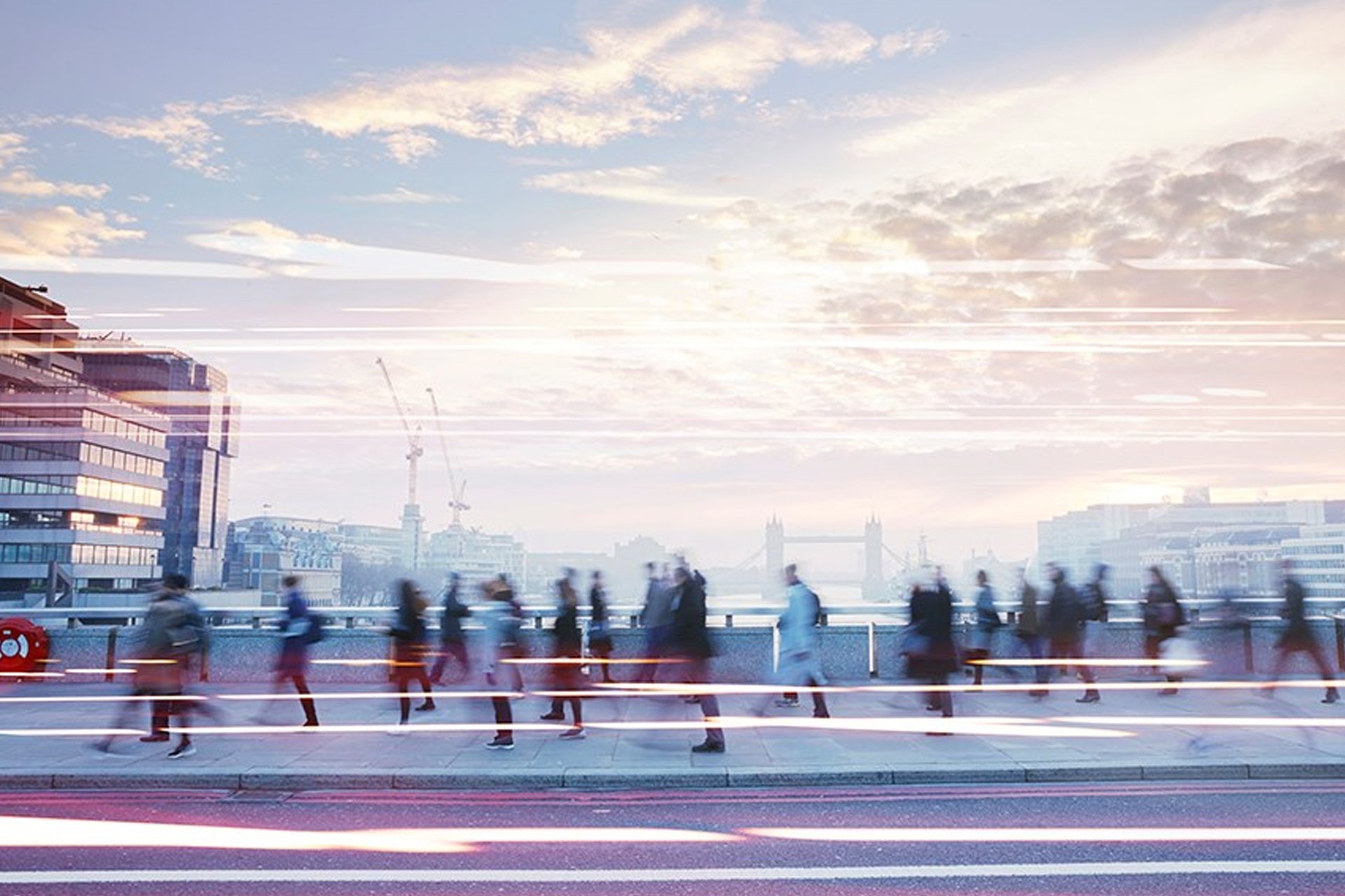 Long exposure of people walking across a bridge in London at dawn.