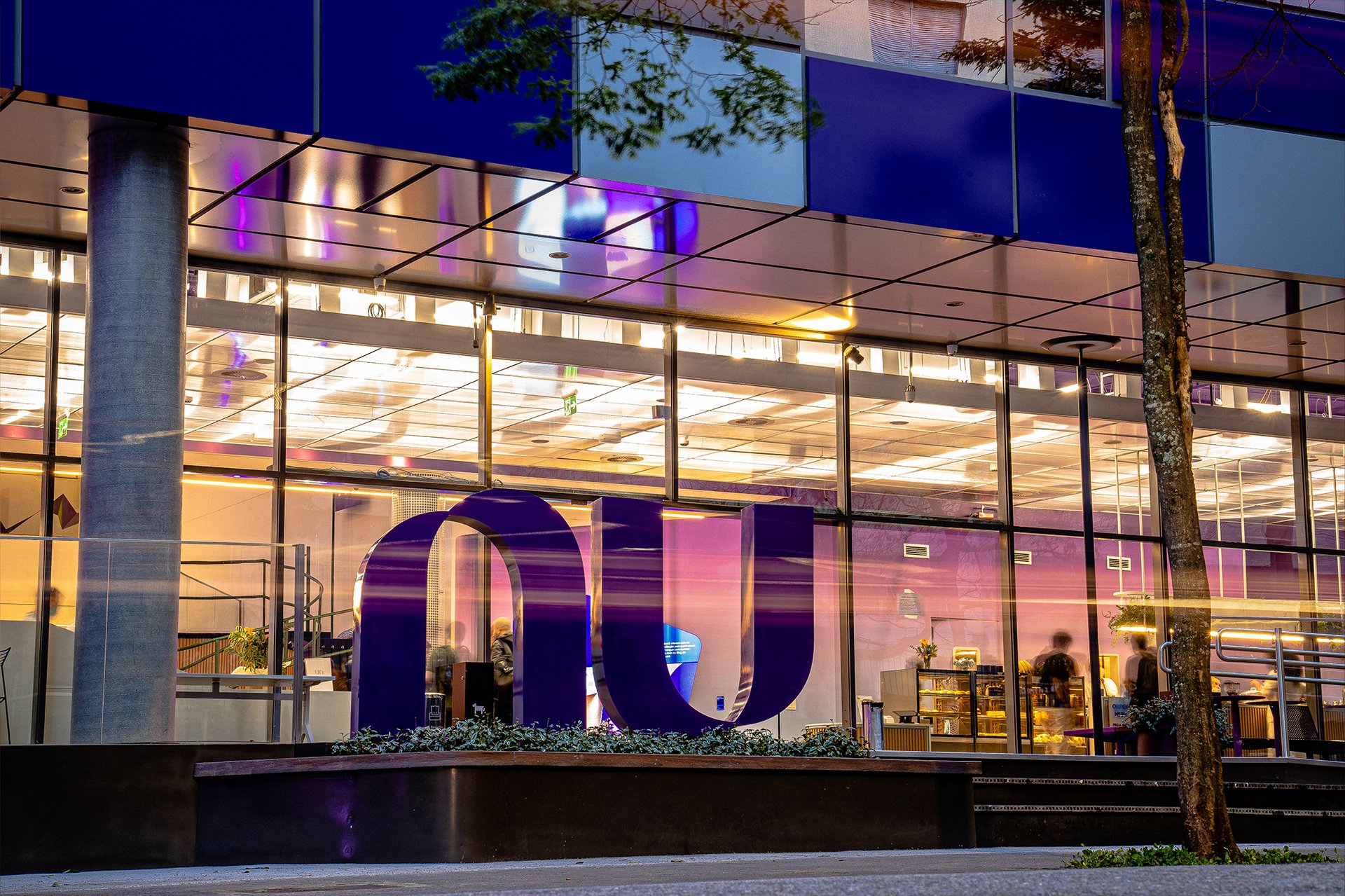 Nubank office at night, with glowing orange and purple lights.
