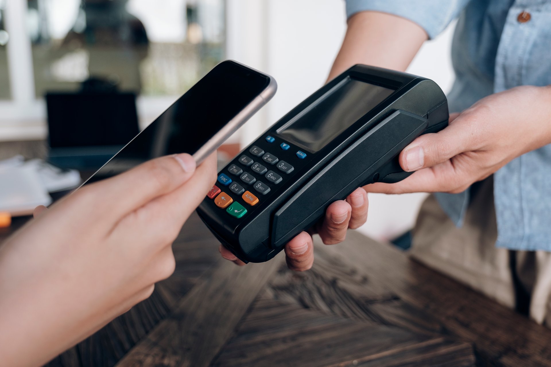 Mobile phone being presented to a payment machine being held by a retailer.