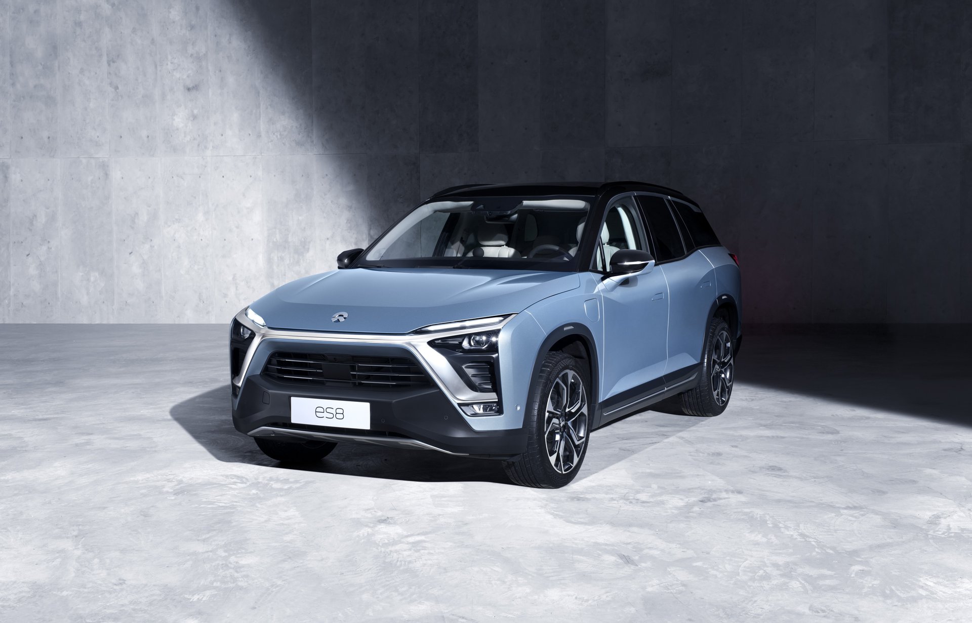 A blue Nio ES8 parked in front of a concrete wall.