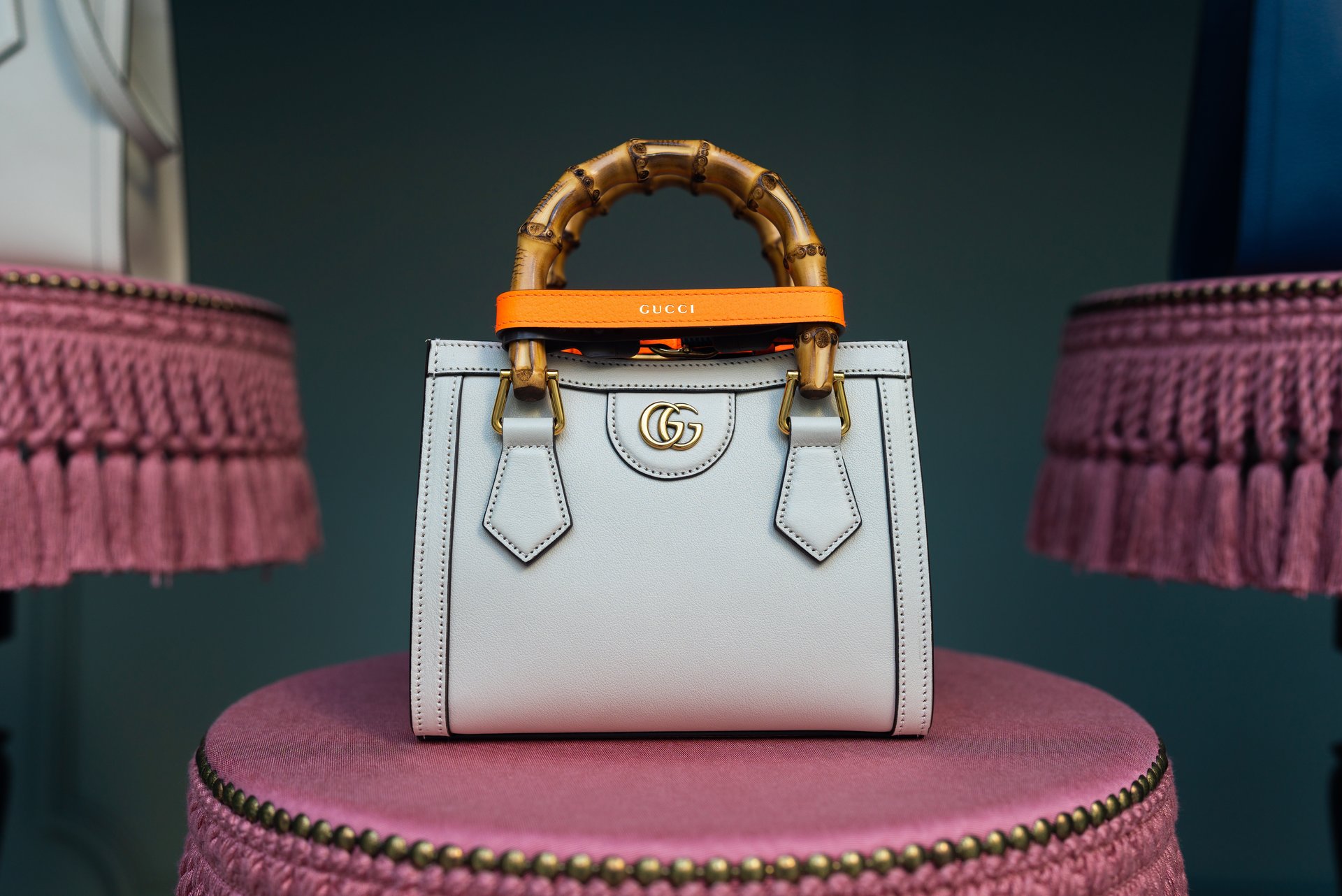 Cream Gucci handbag sat on a pink stool.
