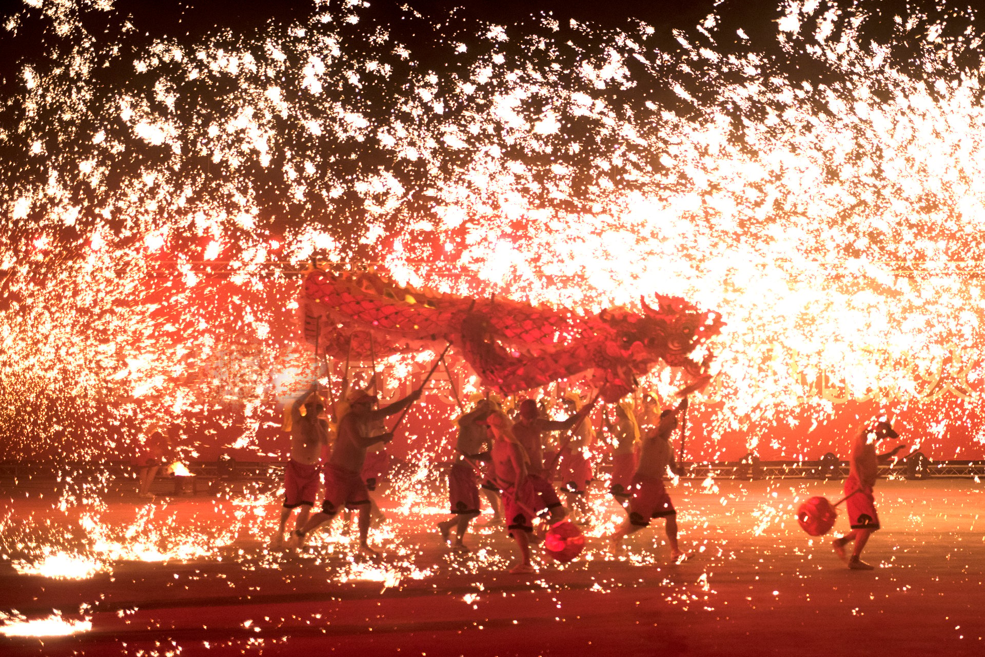 Chinese folk artists performing a dragon dance, creating a unique scene of a dragon flying through the shower of sparking fireworks.