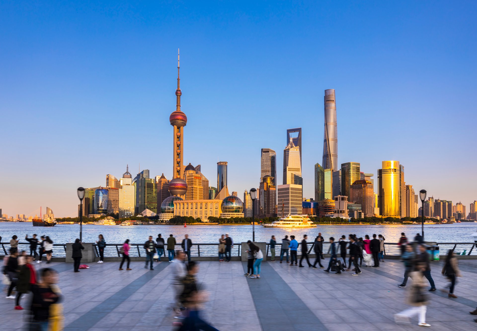 Tourists take photos of skyscrapers in front of a blue sky, in the Pudong business district, Shanghai, China