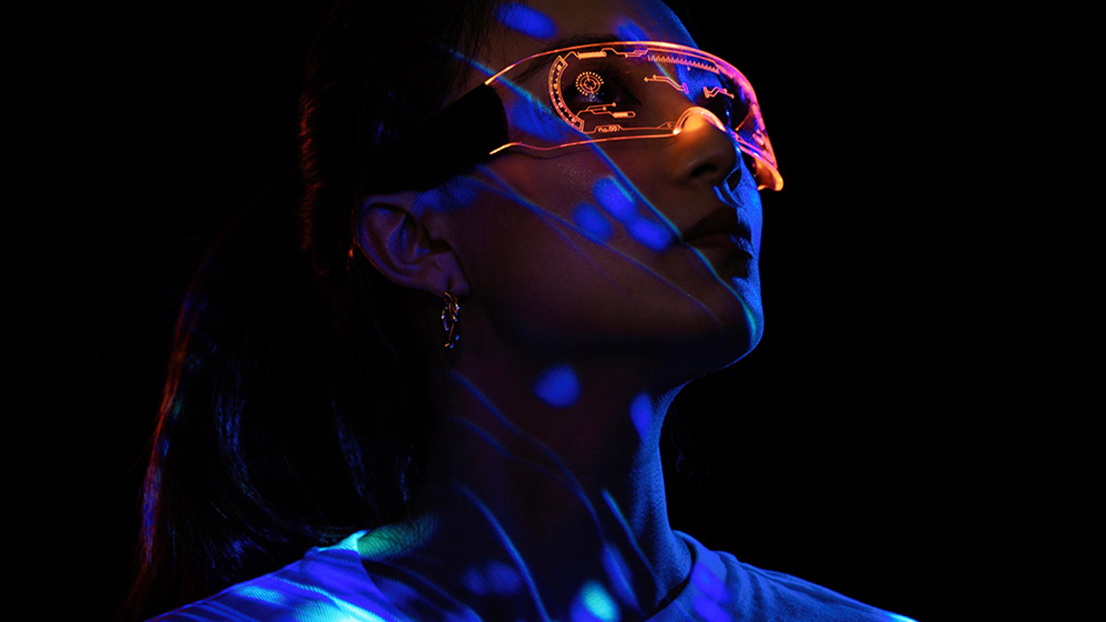 An individual wearing a futuristic visor under a neon blue light.