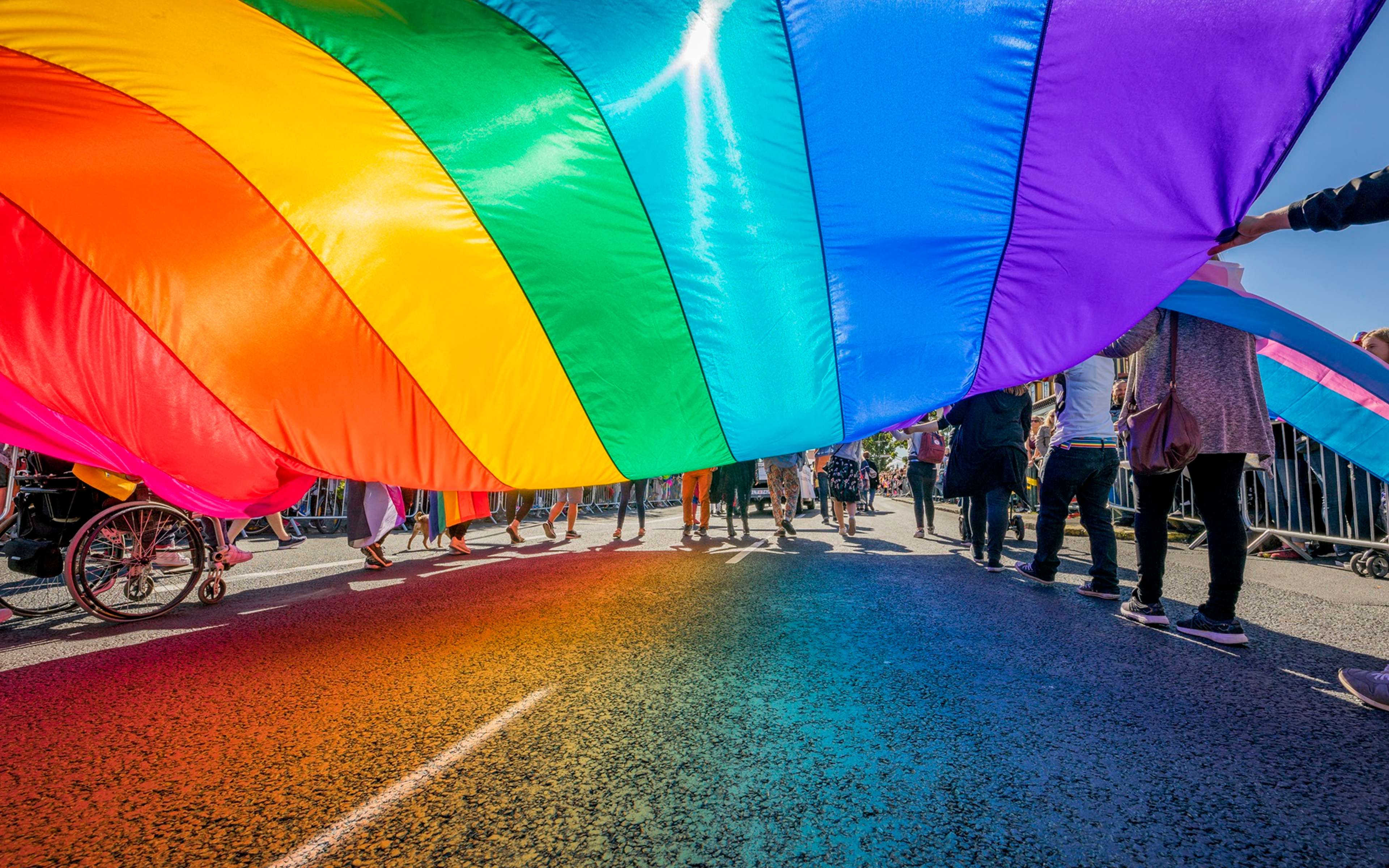 Group holding rainbow flag over road