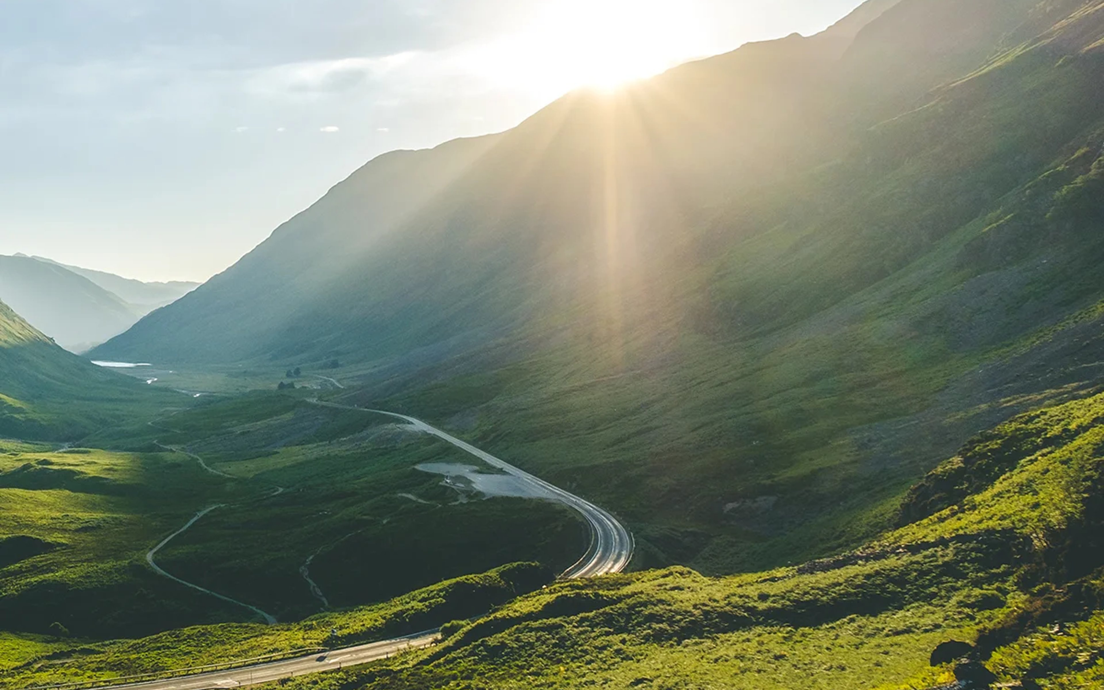 The sun shines above the mountain peaks of GLencoe, Scotland