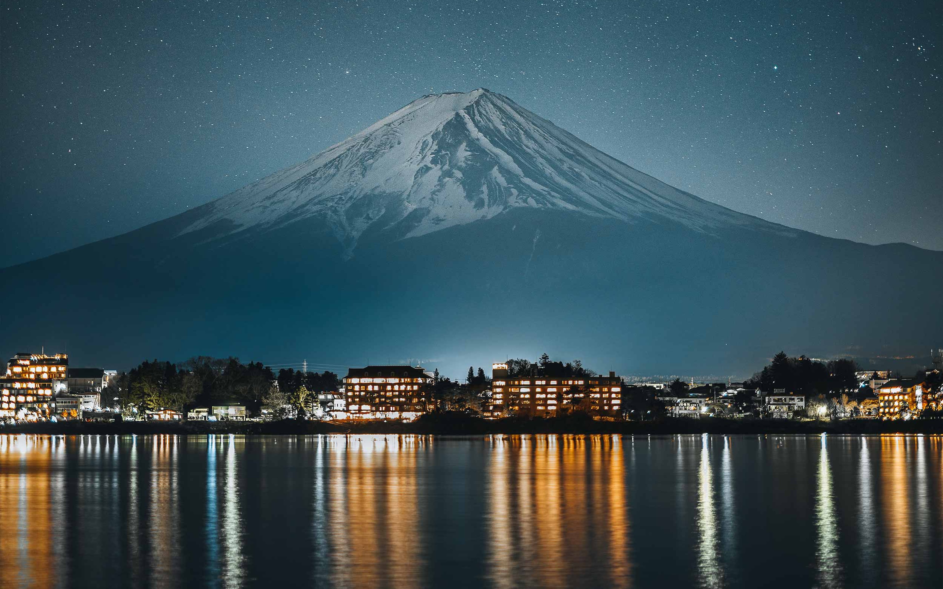 Landscape view of Mount Fuji at night with a starlit sky.