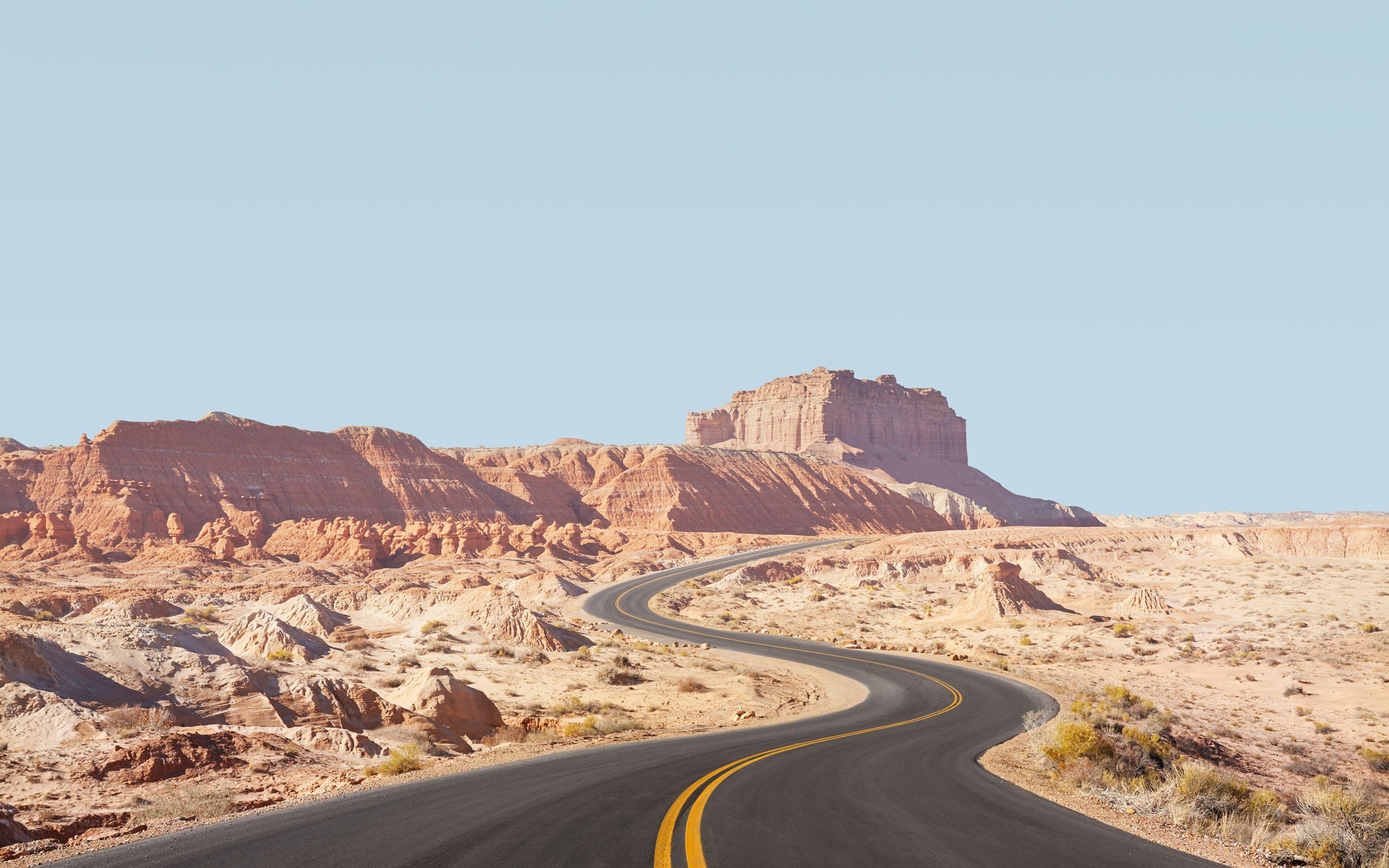 Winding empty road through arid desert landscape.