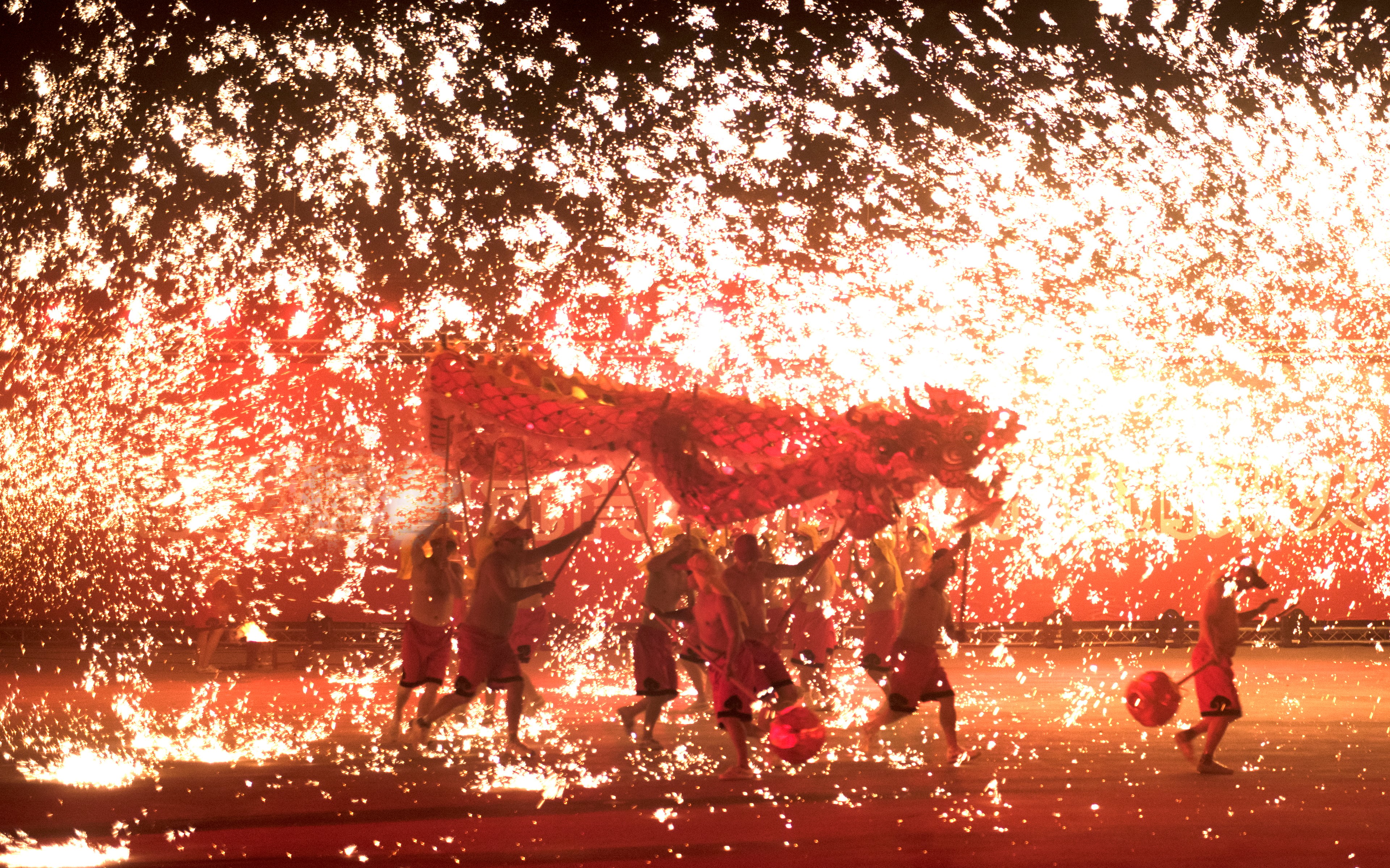 Chinese folk artists performing a dragon dance, creating a unique scene of a dragon flying through the shower of sparking fireworks.