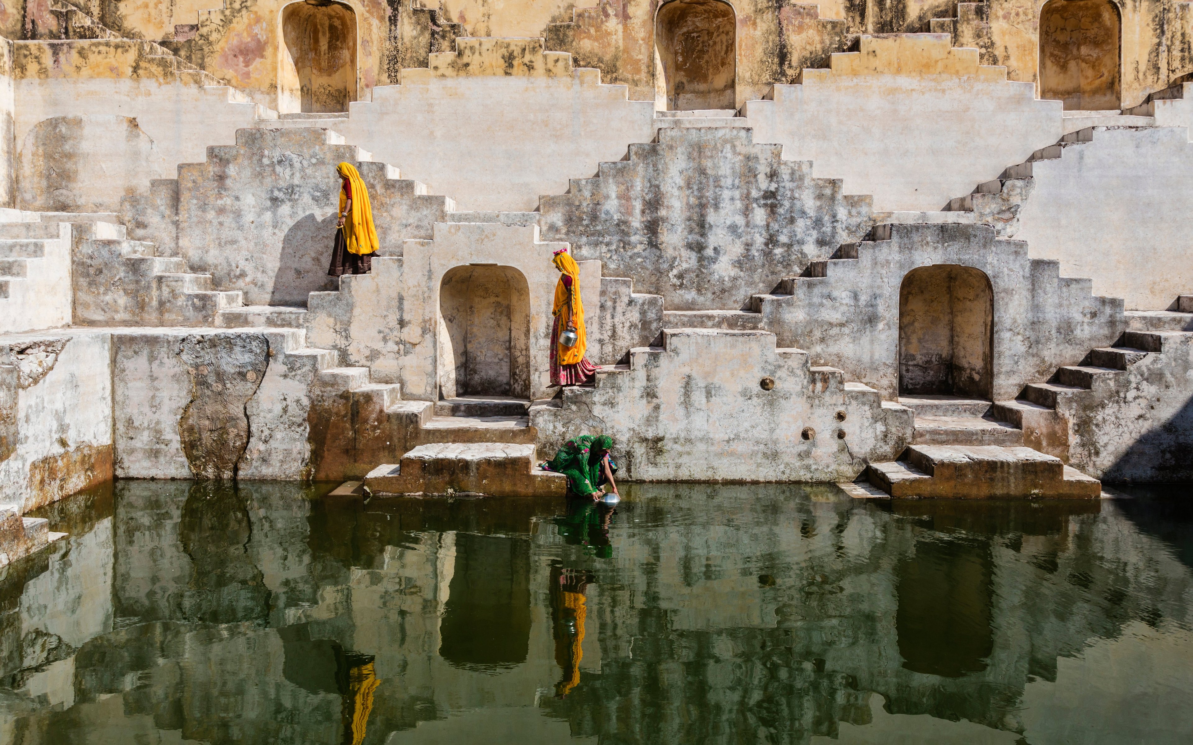 Women in orange saris carrying water at step well in Jaipur, India