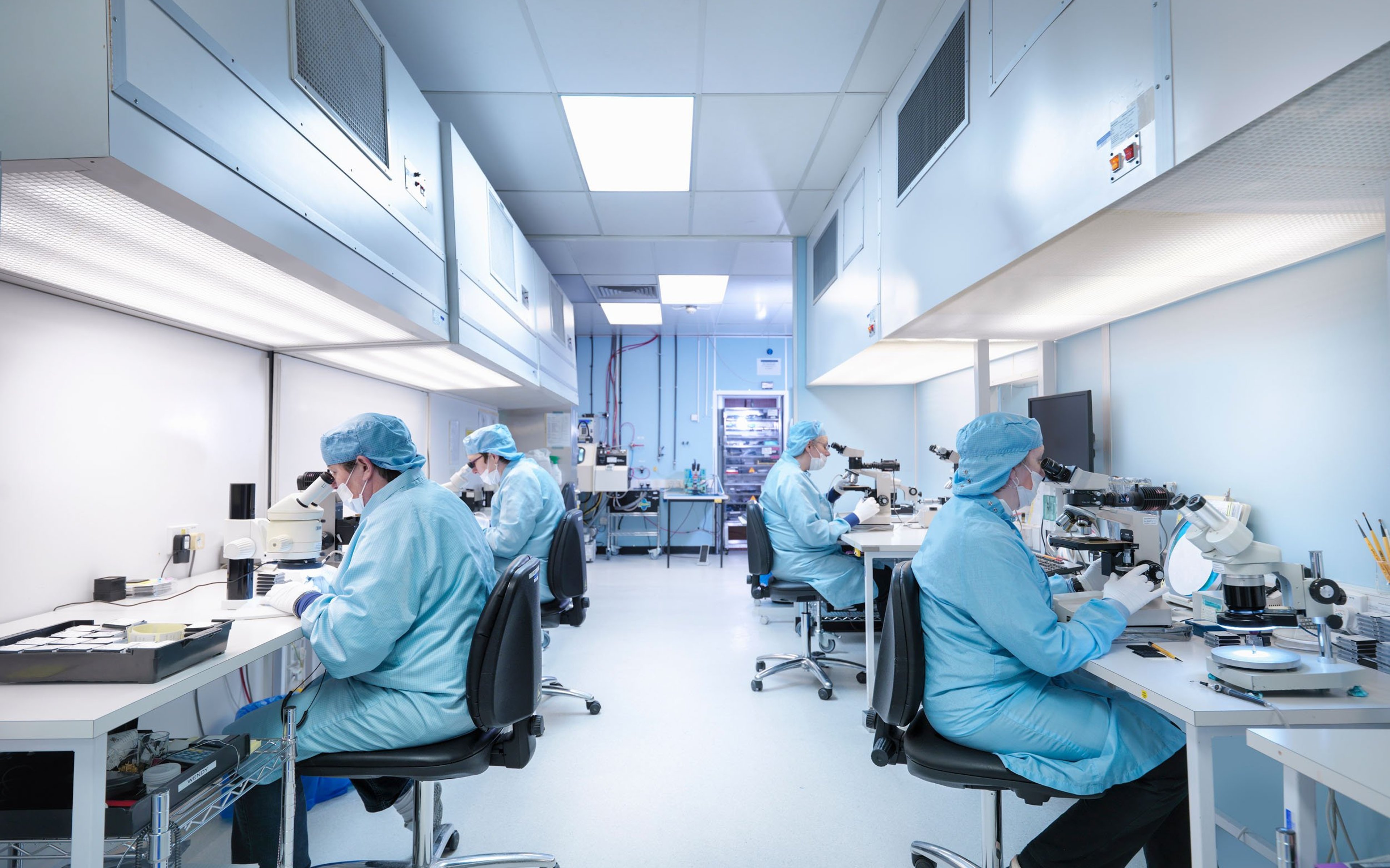 Electronics workers in clean room assembling electronic components.