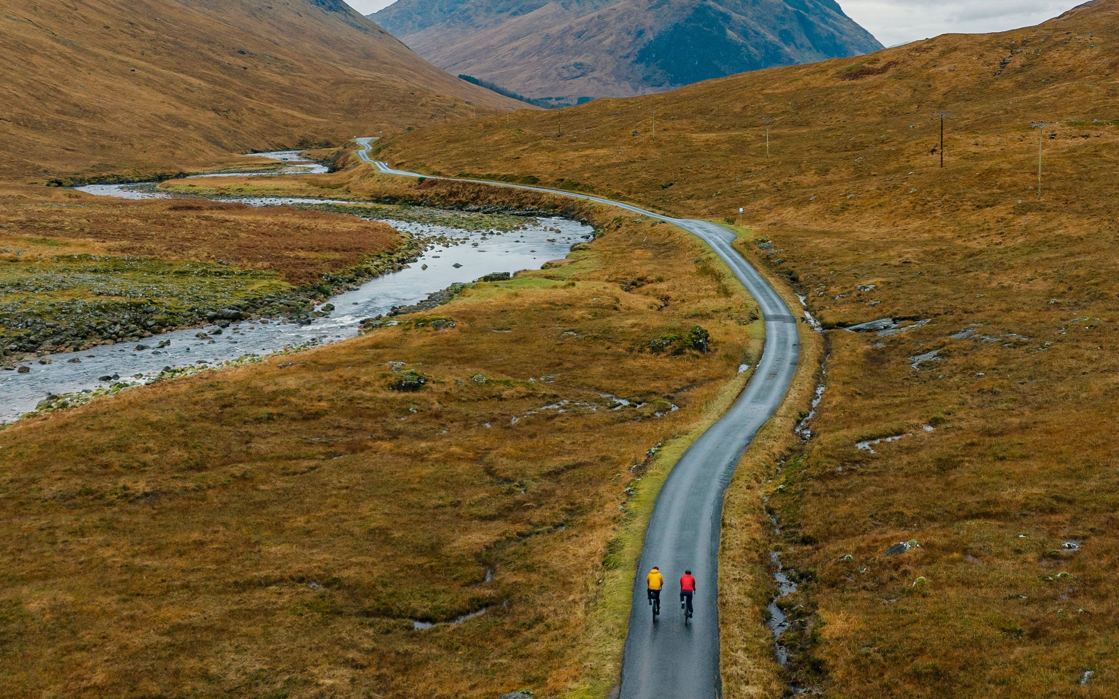 Two adventure cyclists on a single track road in the Scottish Highlands.