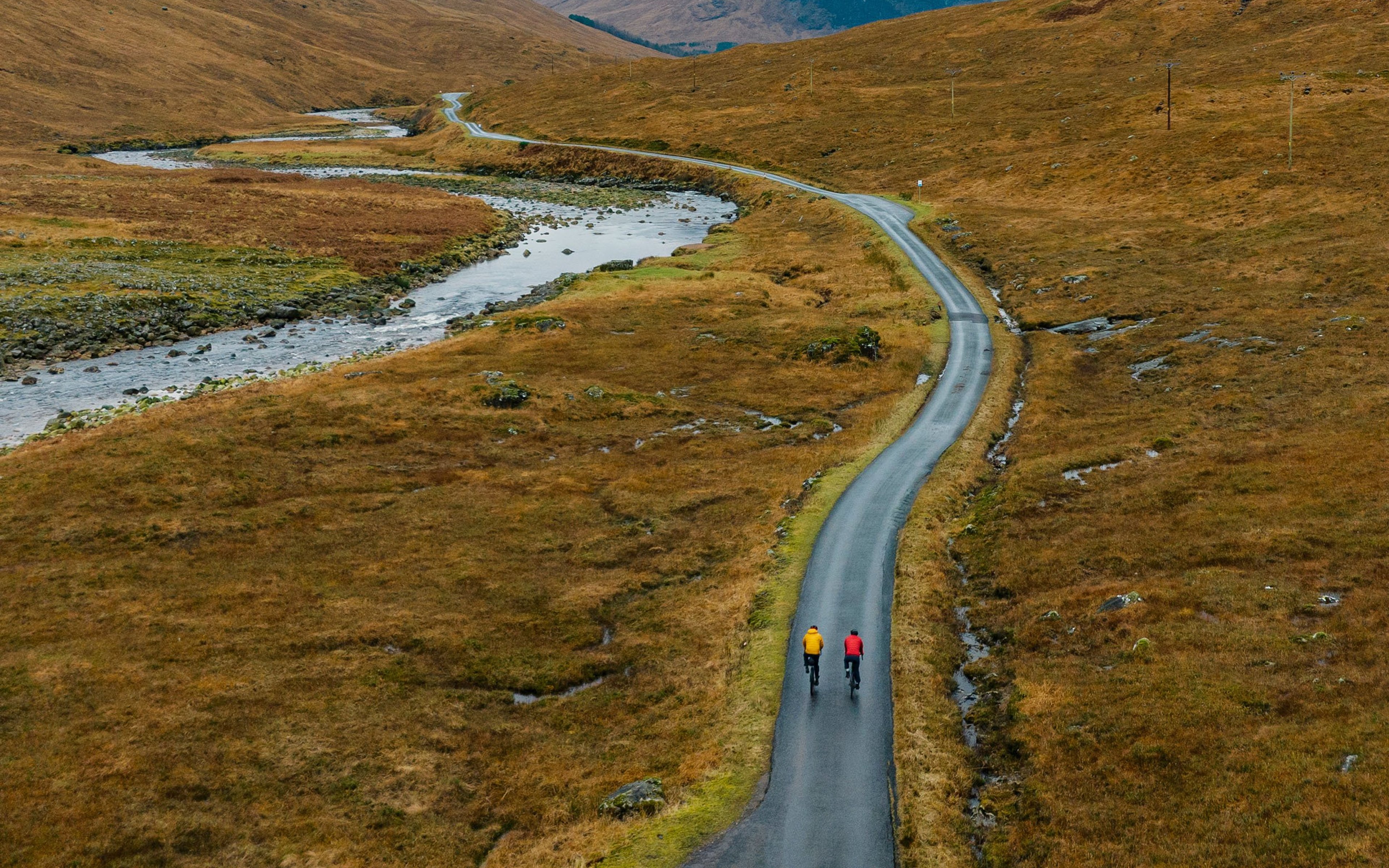 Two adventure cyclists on a single track road in the Scottish Highlands.