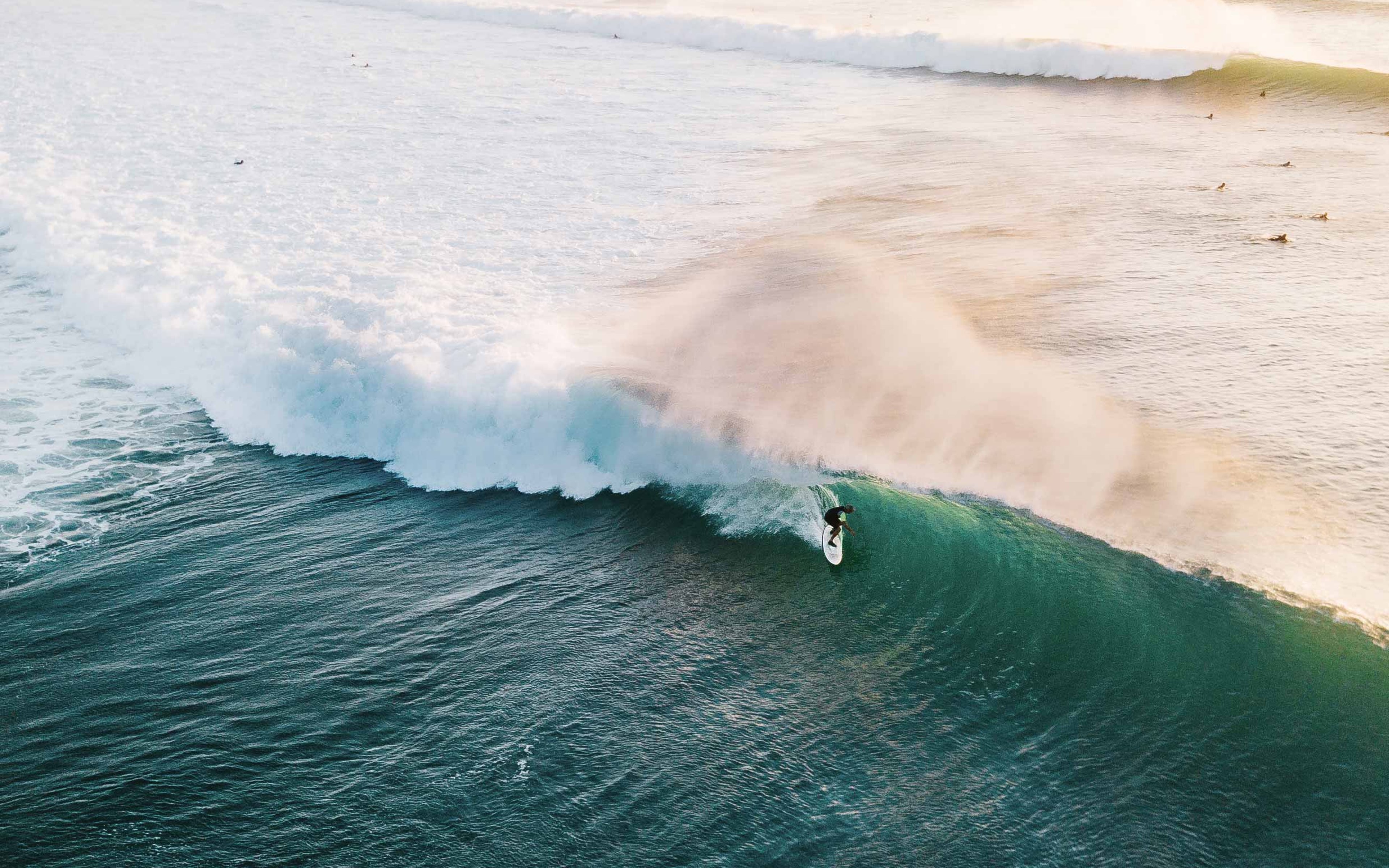 An aerial view of a surfer at the end of a rolling wave.