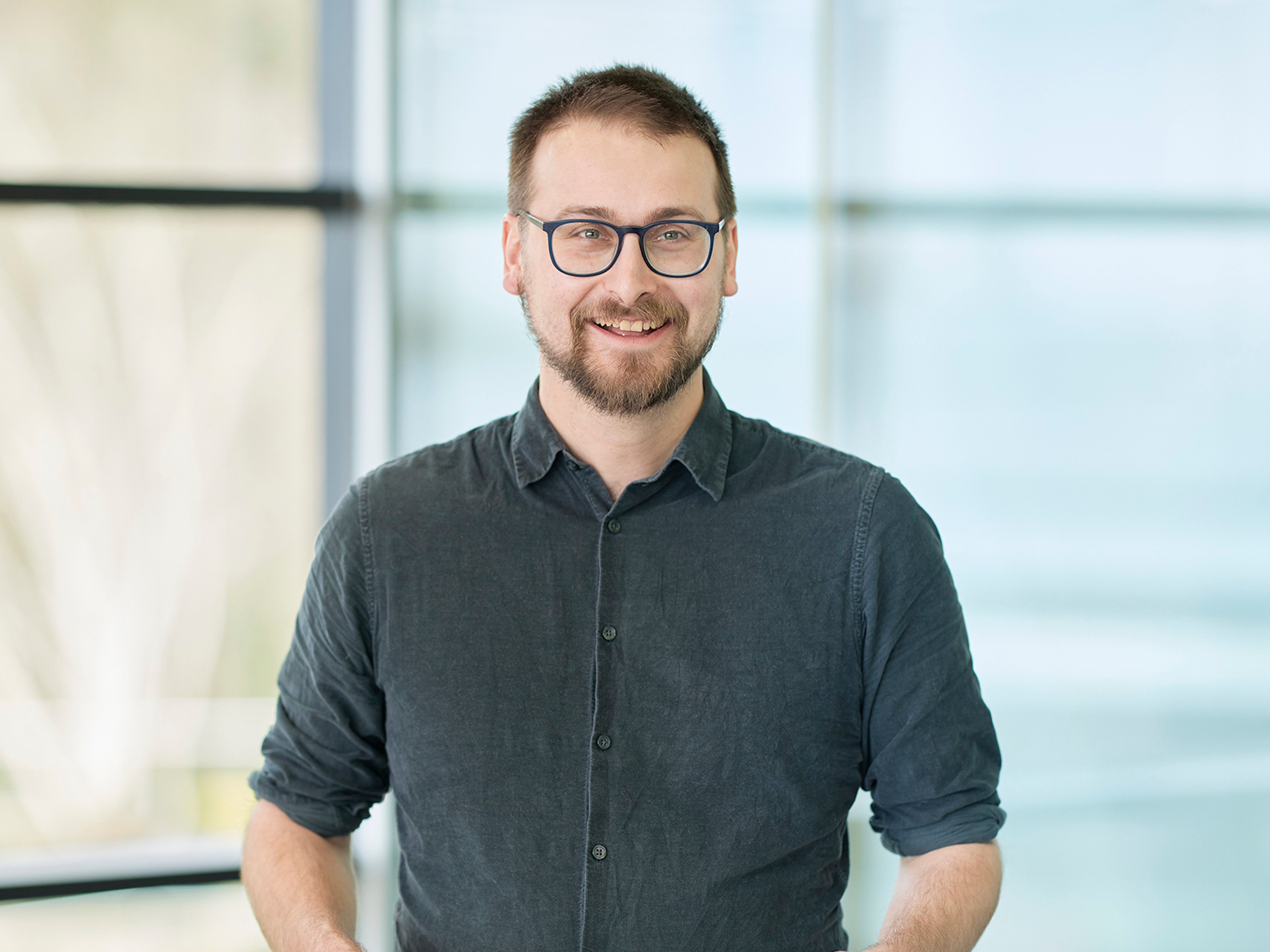Robert Natzler standing while holding a drinks cup.