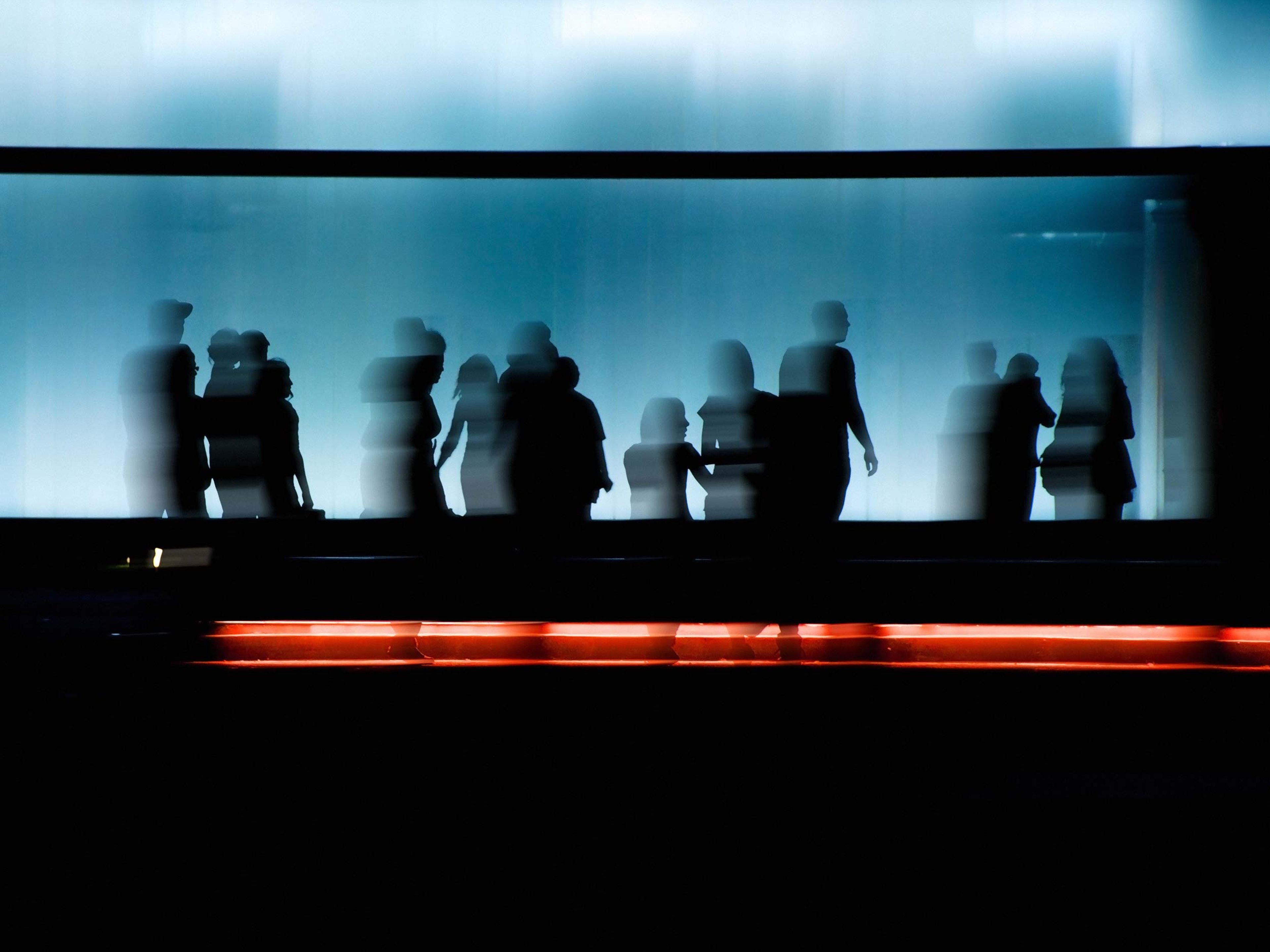Silhouettes of people in motion blur with a red trail of light.