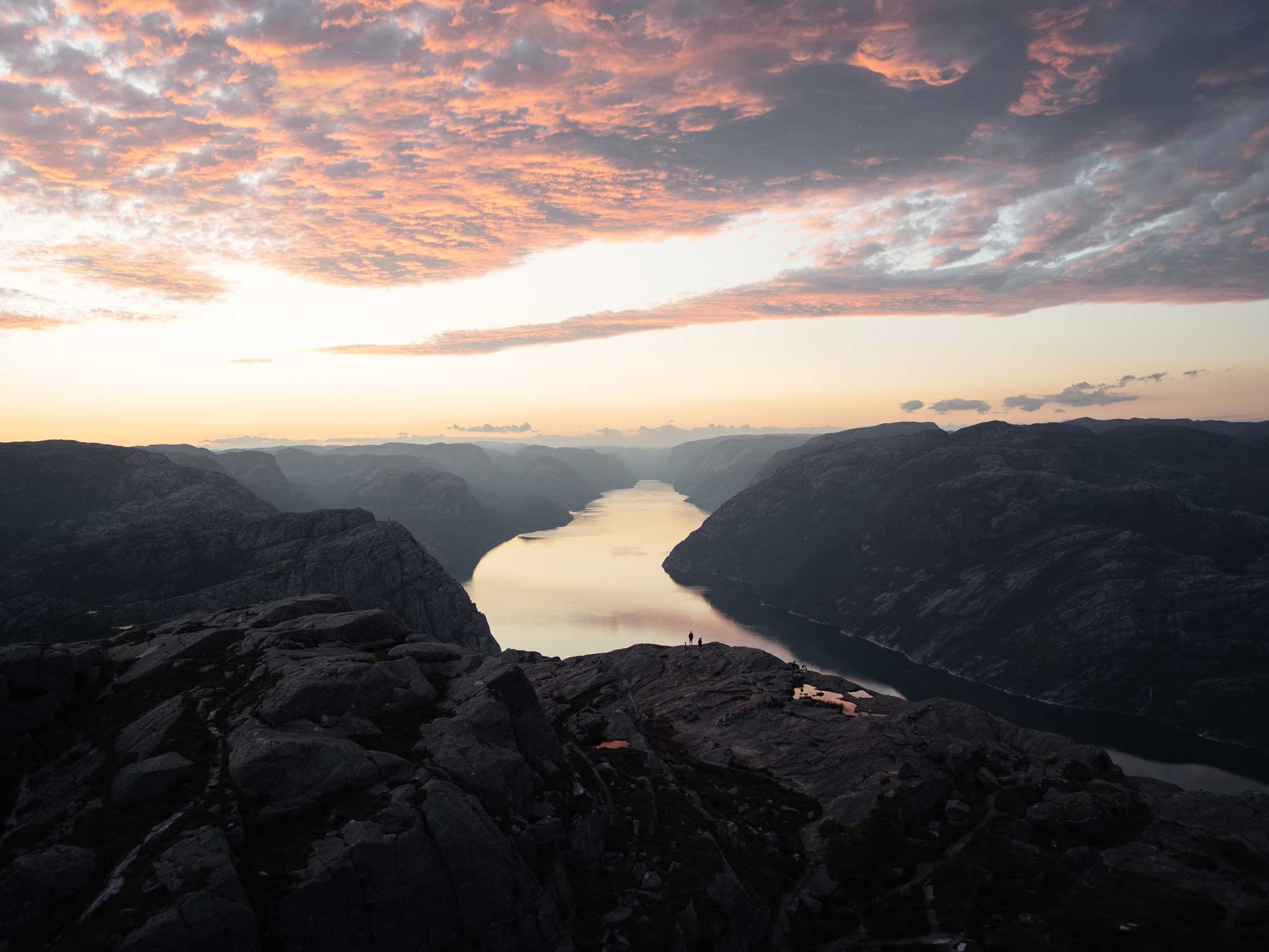 An aerial view of a large lake inside a valley at sunset.