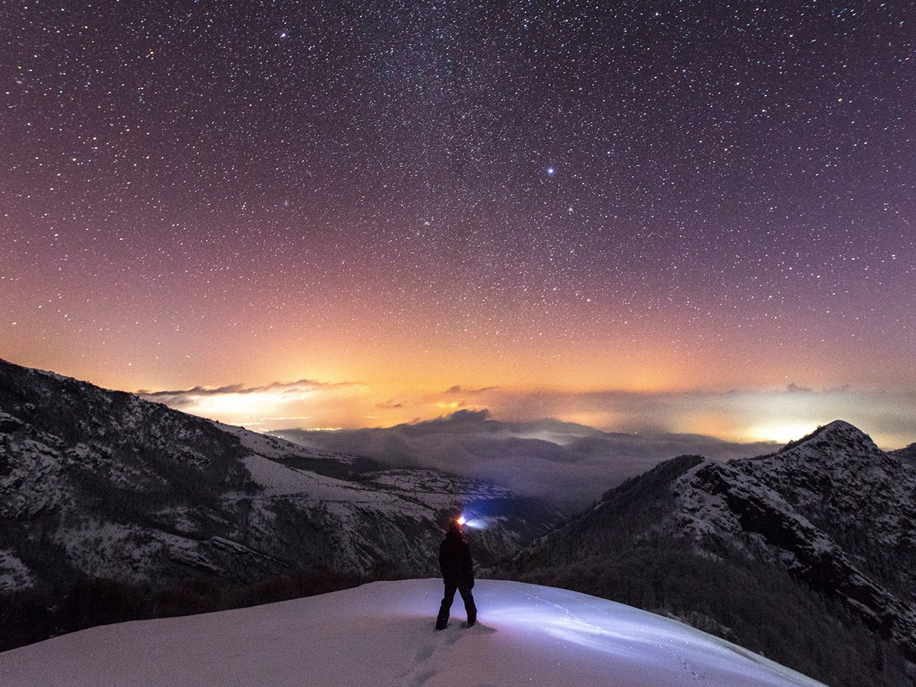 Person on mountain summit with night sky