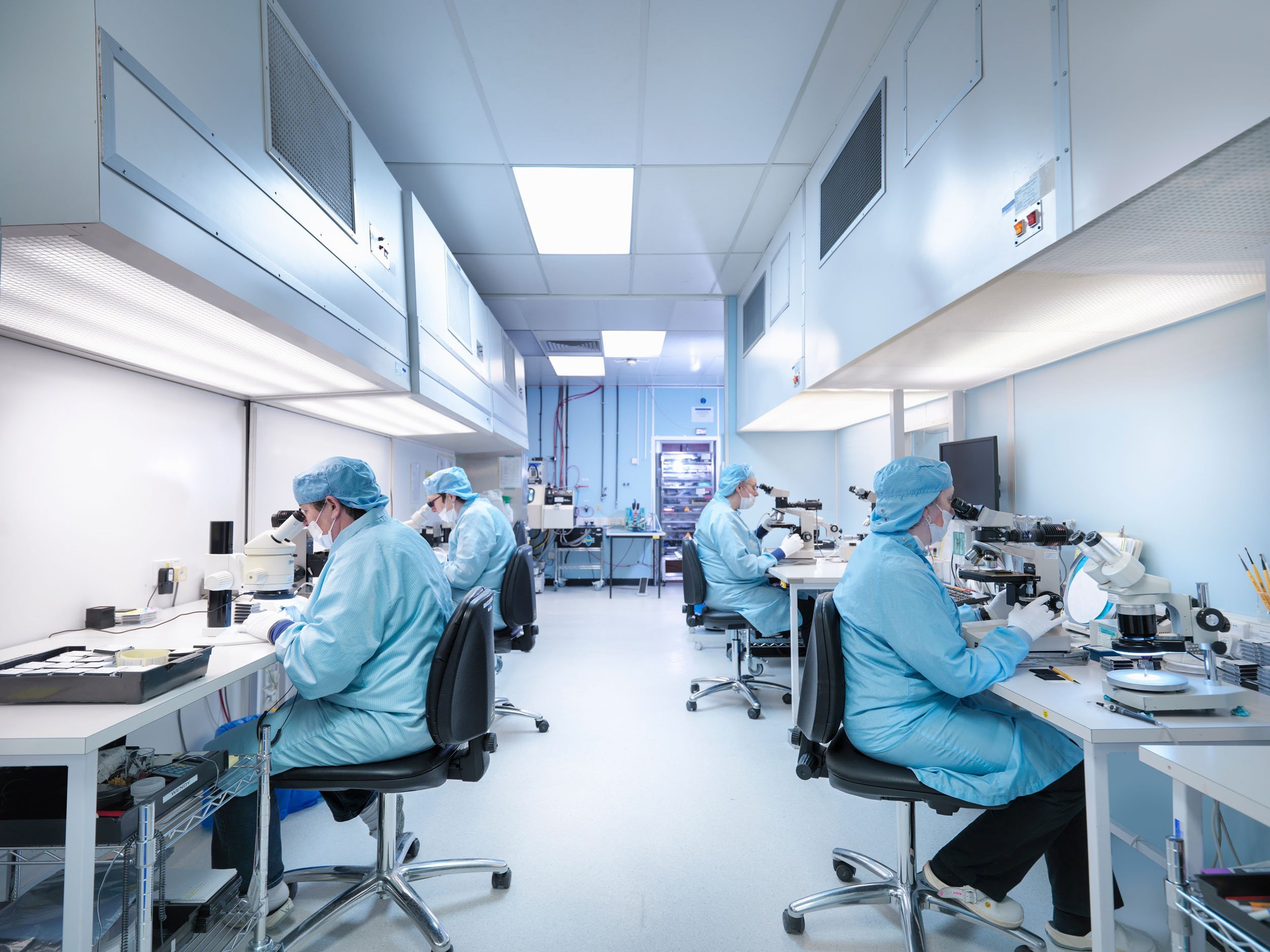 Electronics workers in clean room assembling electronic components.