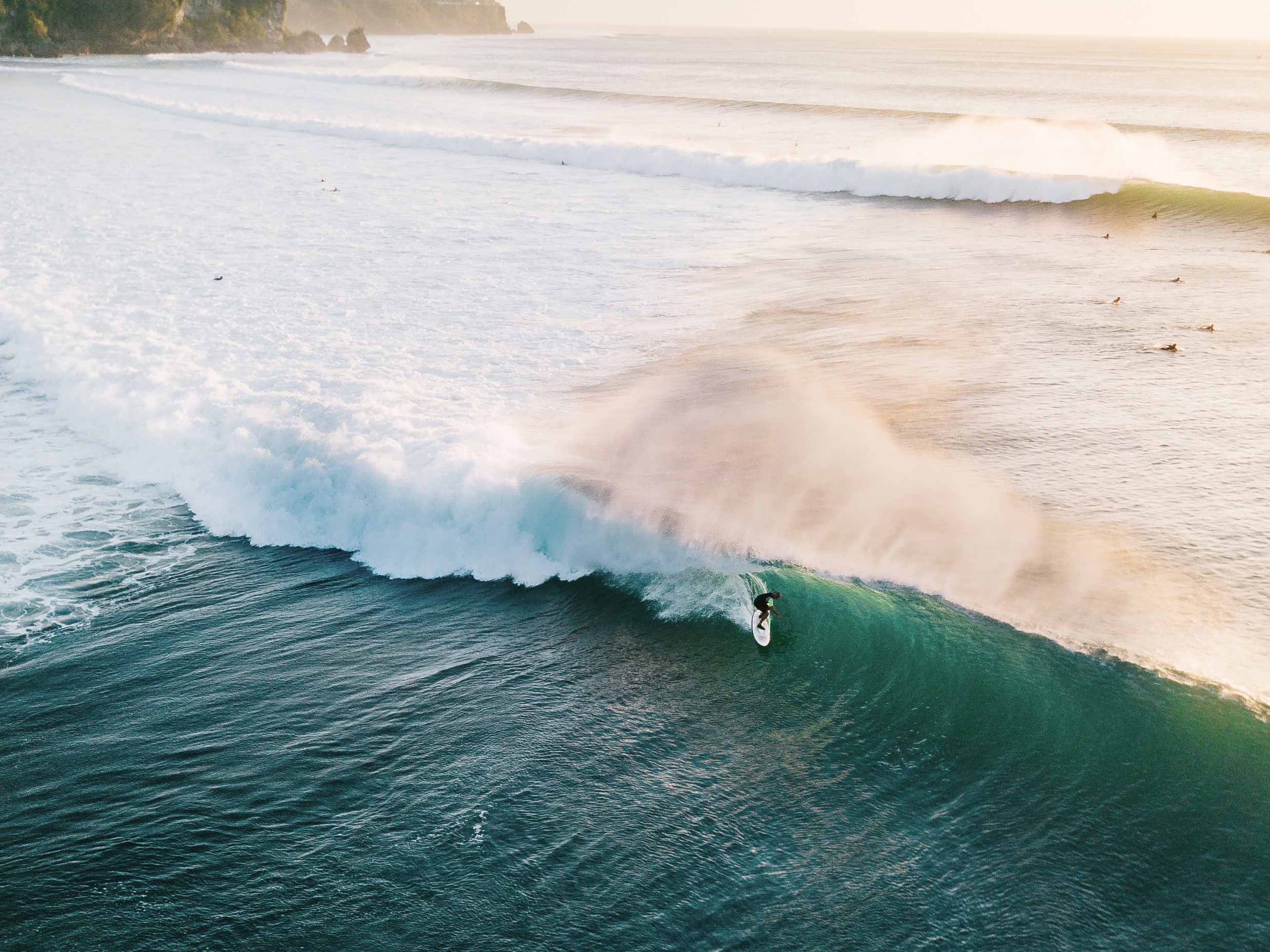 An aerial view of a surfer at the end of a rolling wave.