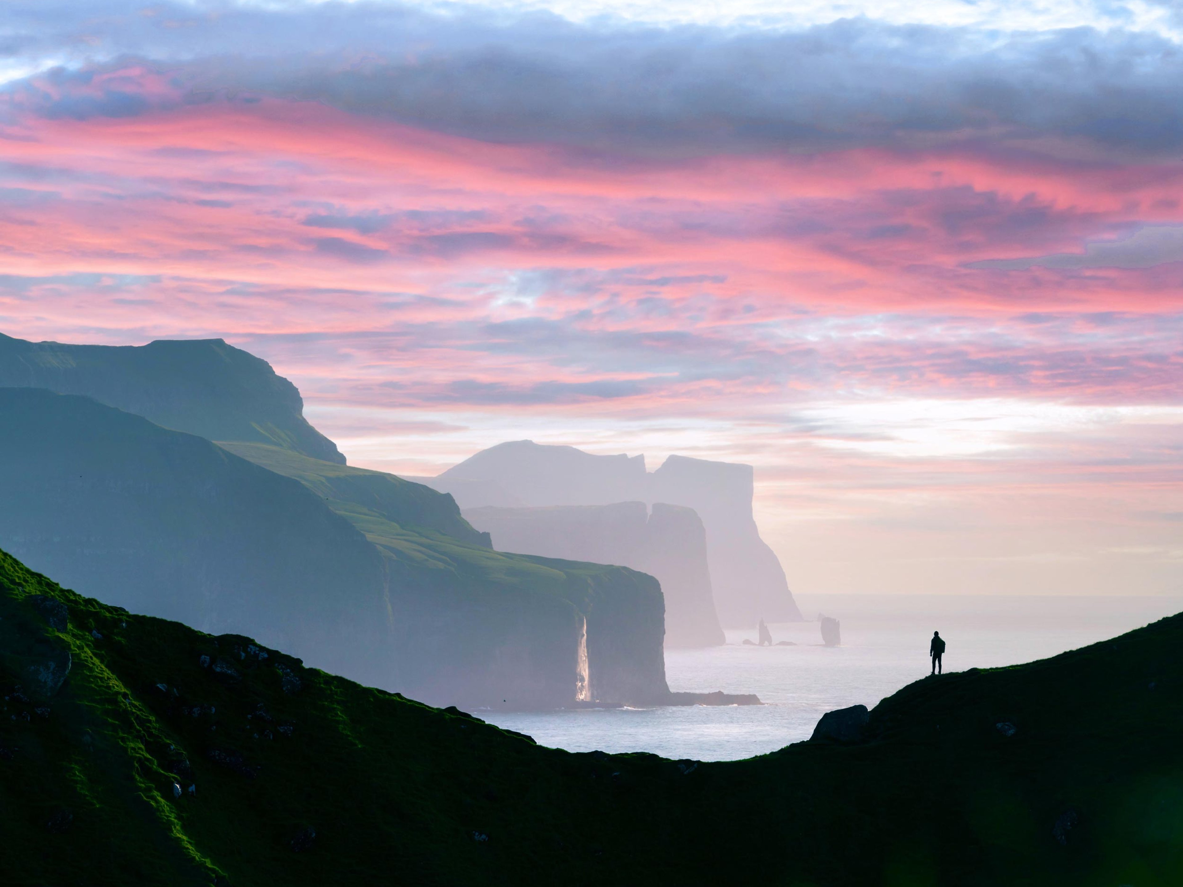 Man silhouette on background of famous Risin og Kellingin rocks and cliffs of Eysturoy and Streymoy Islands seen from Kalsoy Island. Faroe Islands, Denmark. Landscape photography