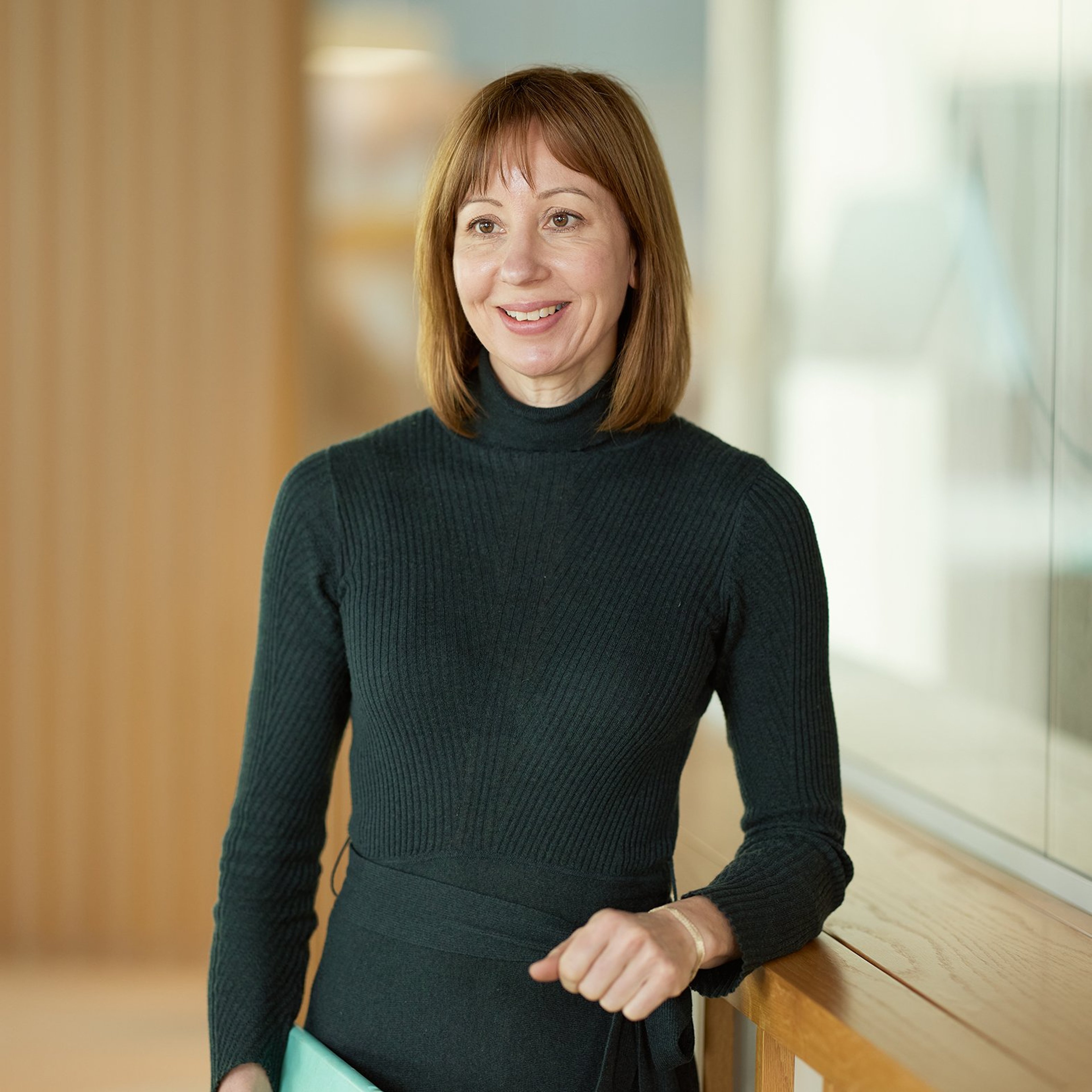 Laura Ingleby standing while leaning against a desk.