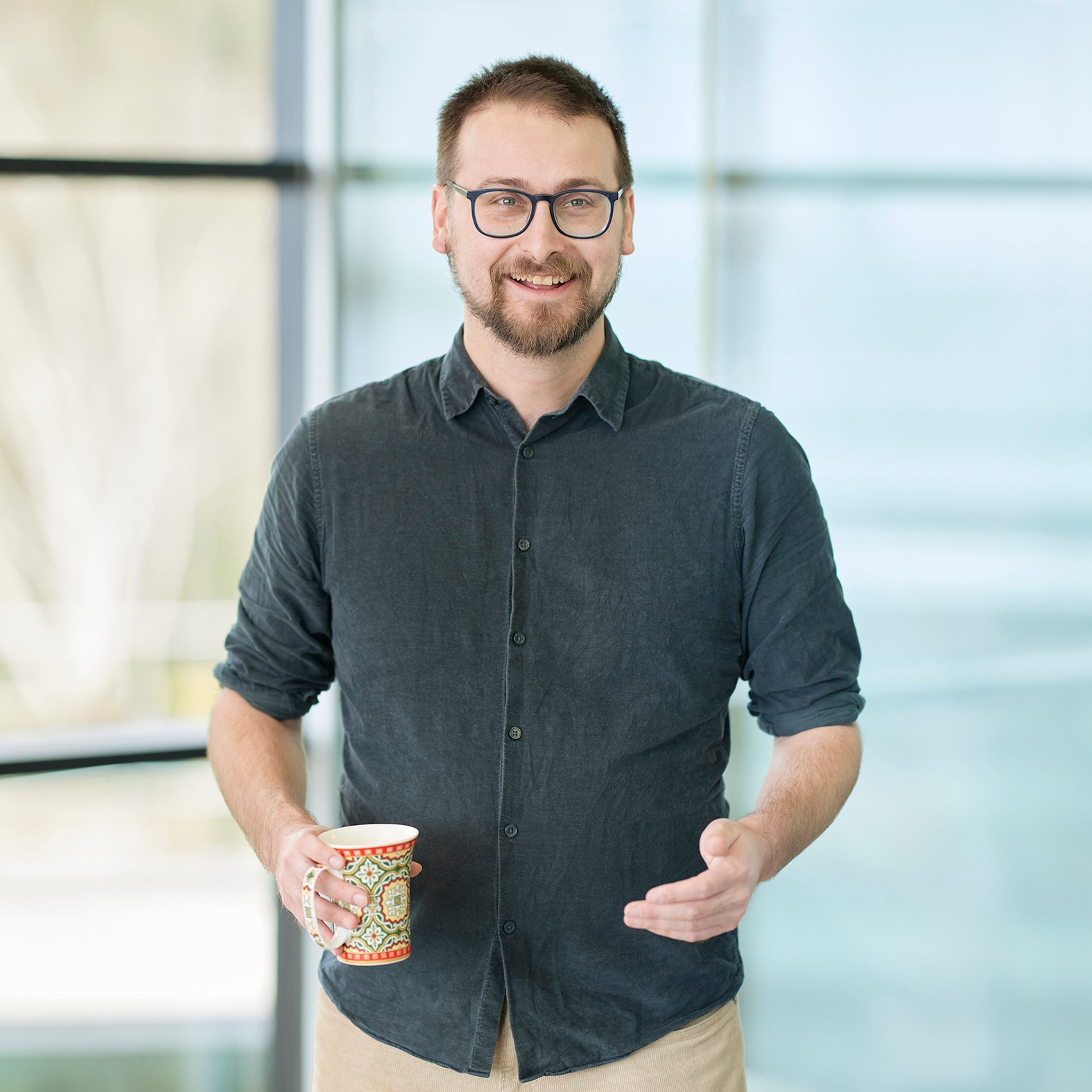 Robert Natzler standing while holding a drinks cup.