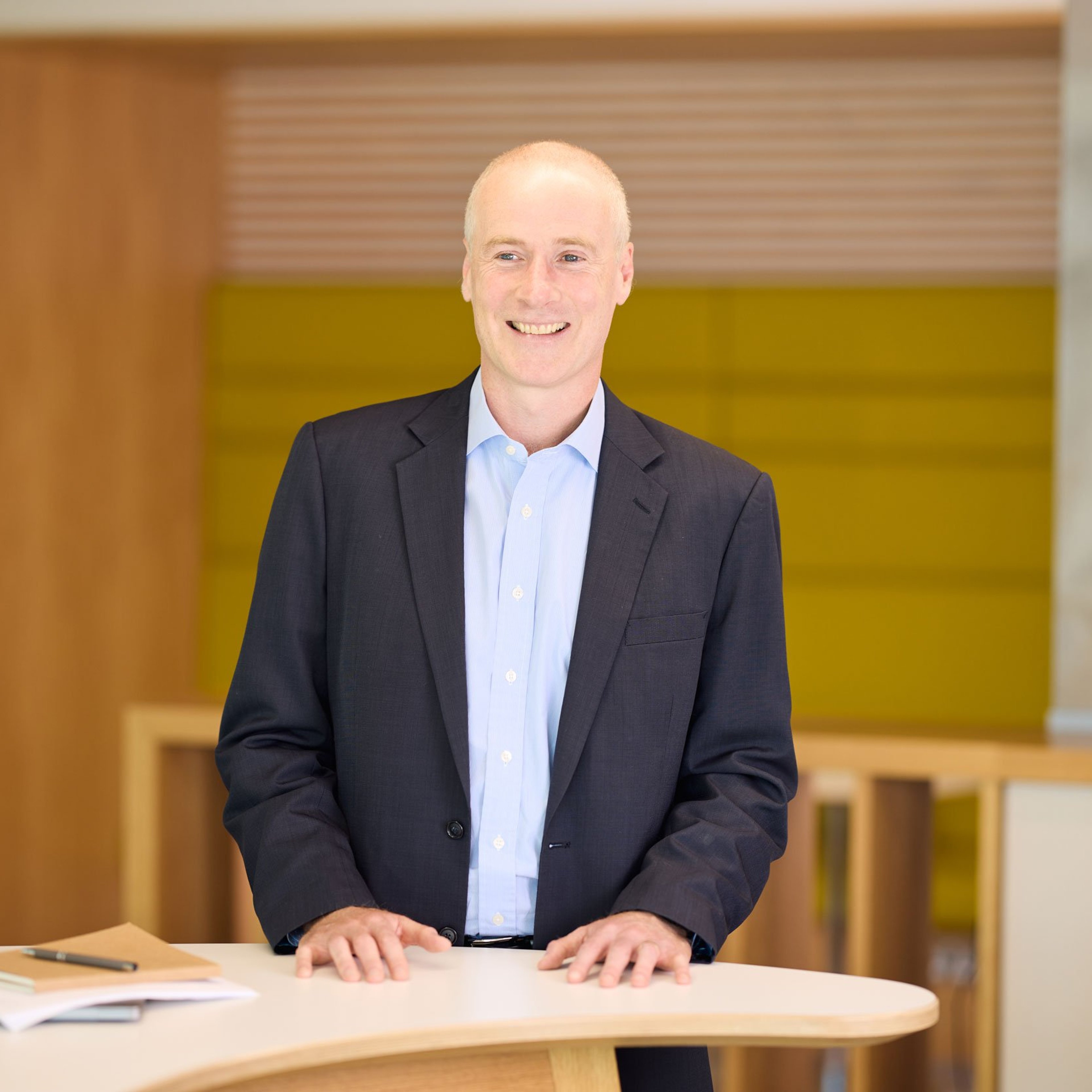 Tim Campbell standing with his hands rested on a desk.
