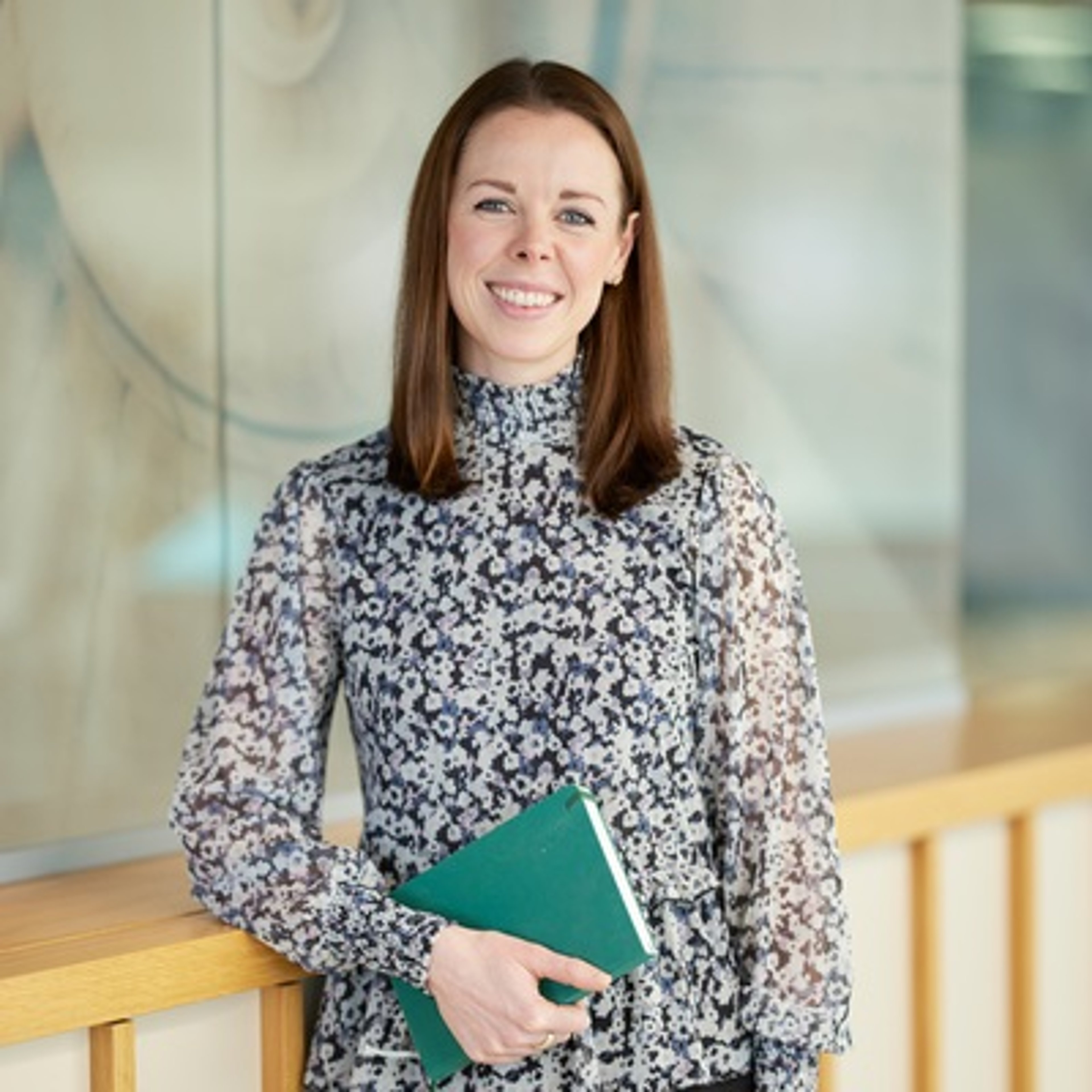 Claire Phillips standing while clutching a notebook in the Baillie Gifford office.