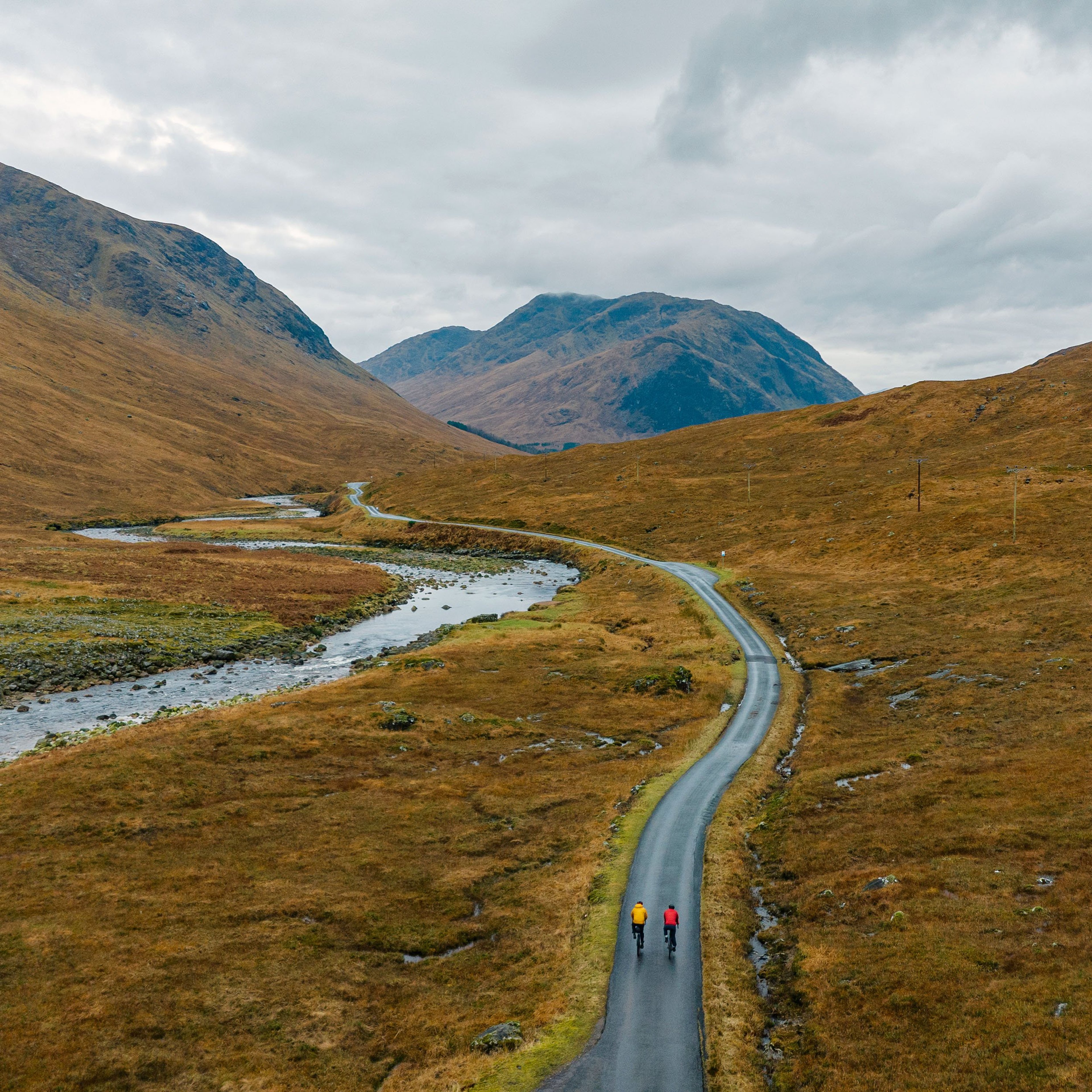 Two adventure cyclists on a single track road in the Scottish Highlands.
