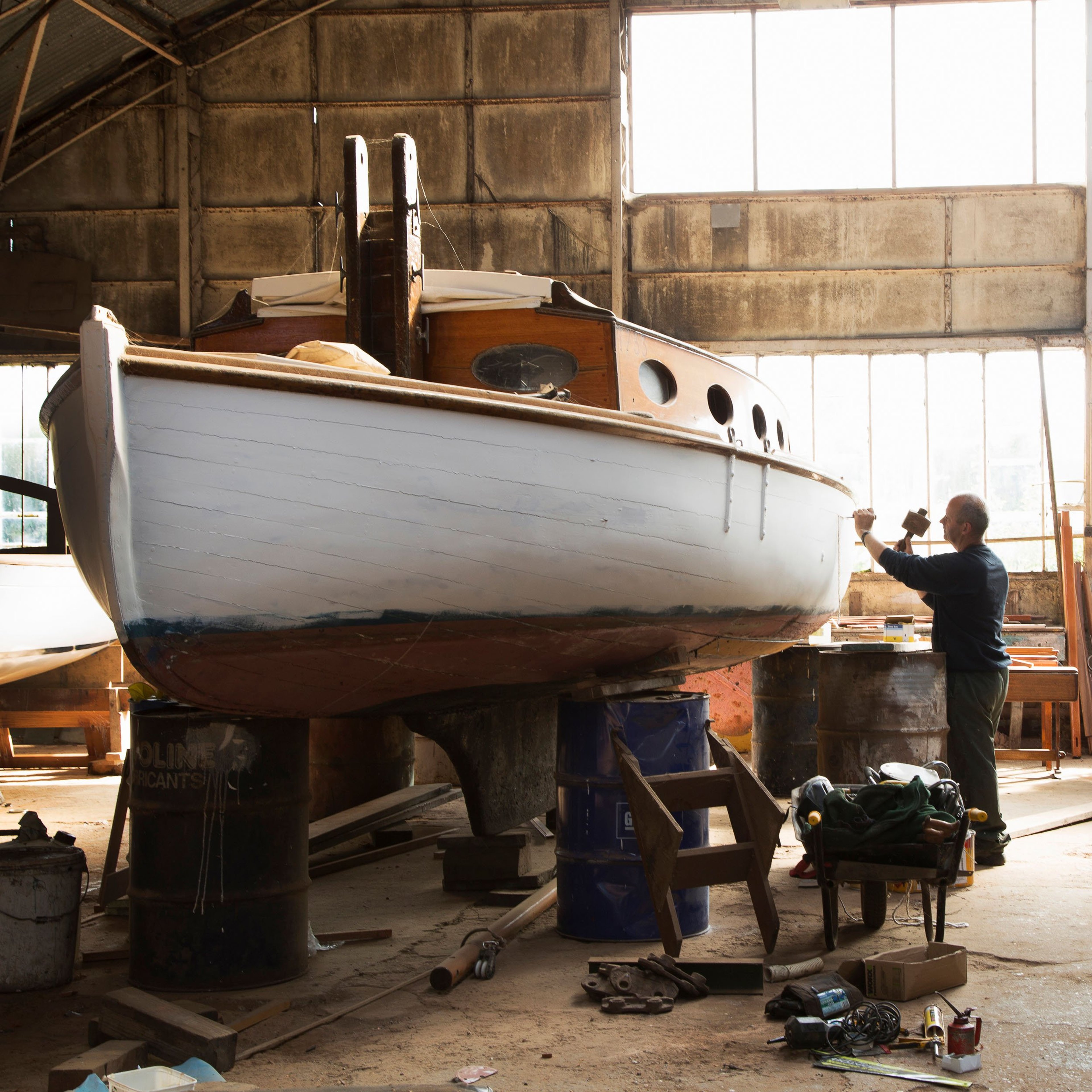 Skilled craftsman reconditioning old sailing boats in boat yard near Norfolk Broads UK.