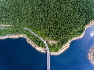 Arial view of a road bridge over a lake and mountain forest